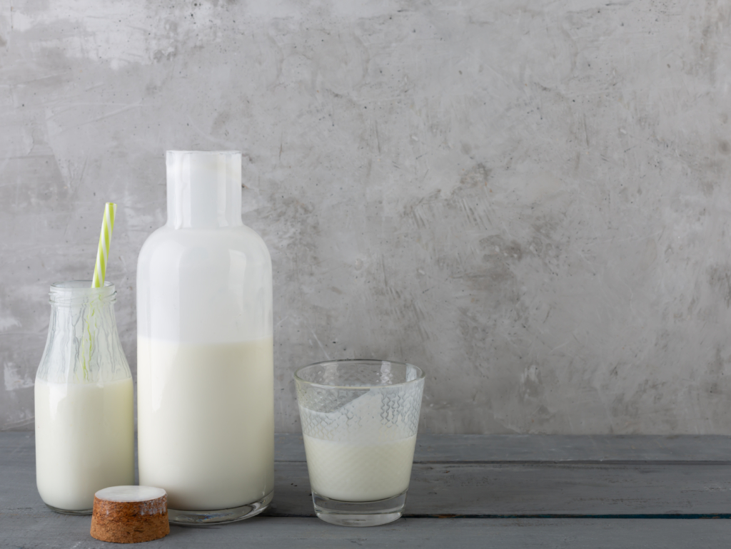 Milk drink in a bottle and glasses with on the gray wooden background